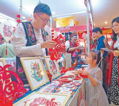 日前，在缅甸仰光举办的“欢乐春节·新春集市”活动现场，工作人员在展示剪纸作品。本报记者 谢佳君摄